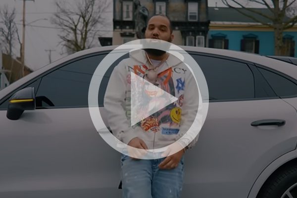 man standing in front of a car with play button on top of image