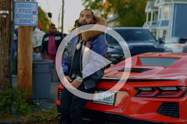 man leaning against the back of a red sports car